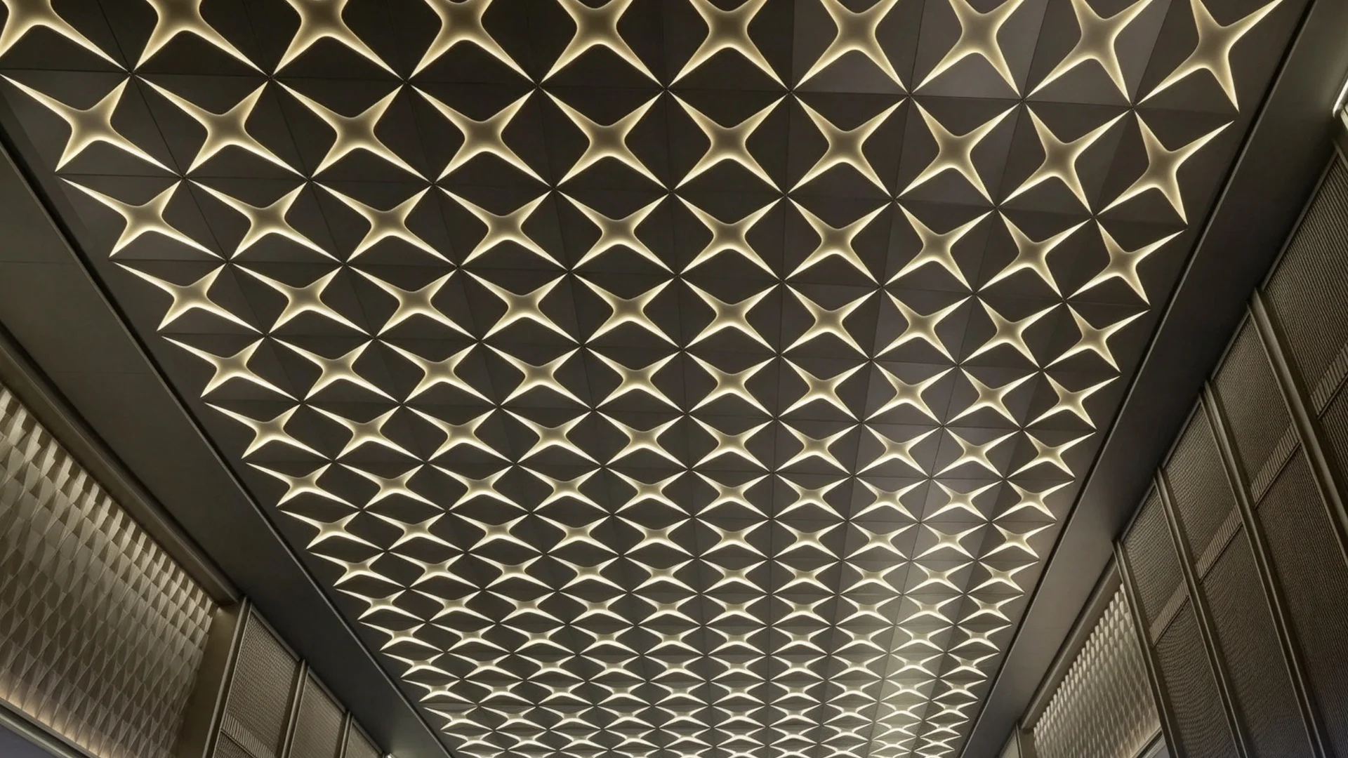 Ceiling light strip effect of Lindelacr four-leaf petal shaped aluminum veneer for indoor ceiling. Square modules are arranged in continuous layout, with warm white light strips embedded in the gaps to create rhythmic geometric light and shadow, enhancing the artistic sense and high-end texture of commercial spaces.