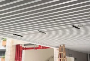 Guangzhou Baiyun University corridor: white U-shaped aluminum baffles with recessed linear lights during teaching-building retrofit
