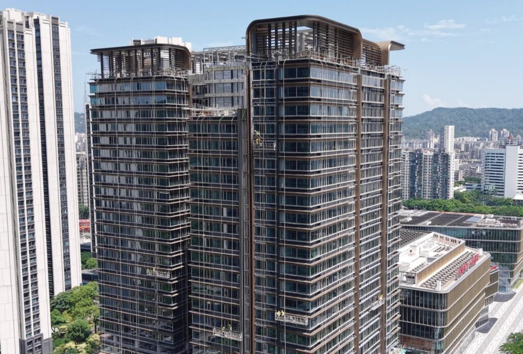 LINDELACR custom metal cladding on a commercial tower: bronze-tone aluminum framing and glass during envelope installation