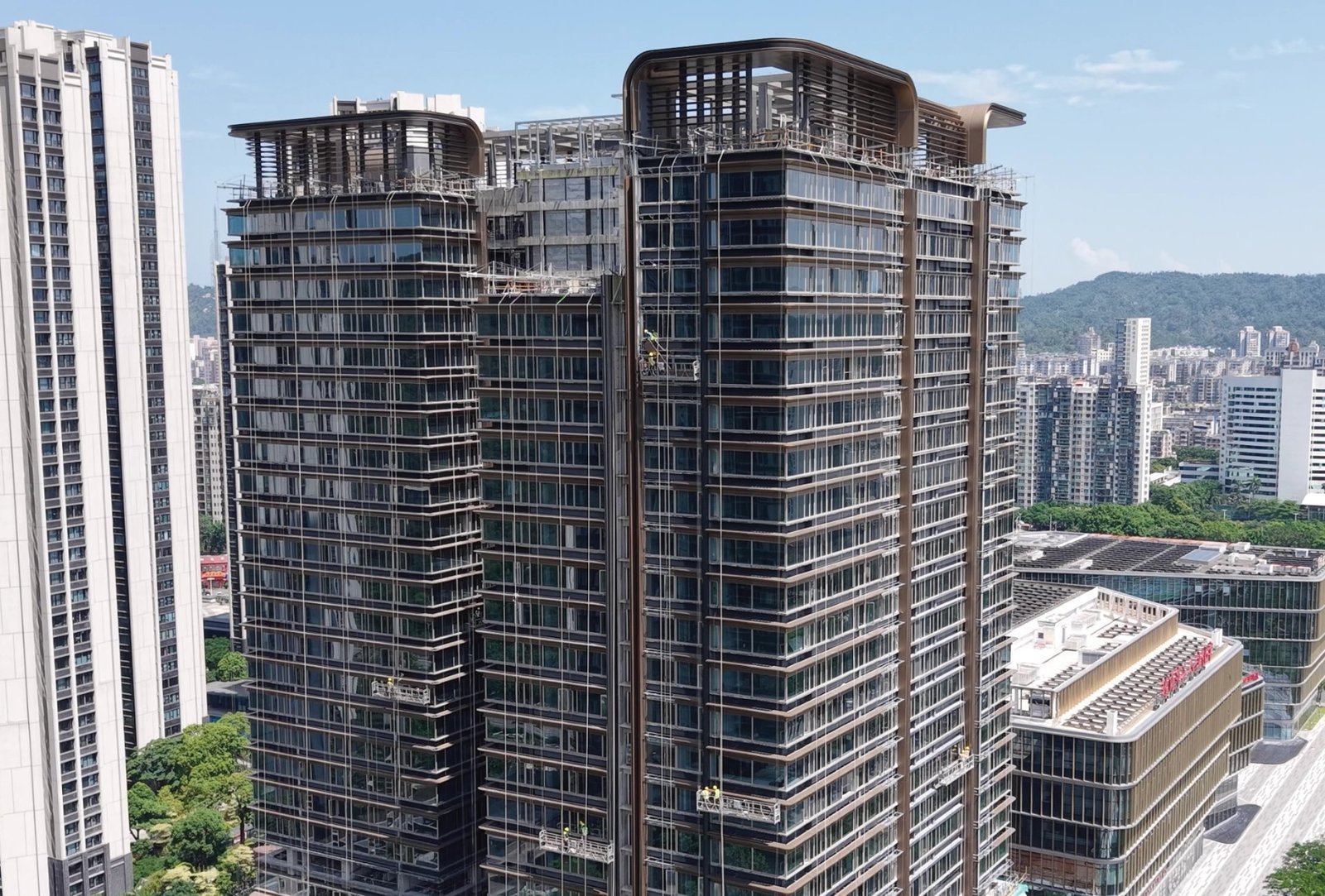 LINDELACR custom metal cladding on a commercial tower: bronze-tone aluminum framing and glass during envelope installation