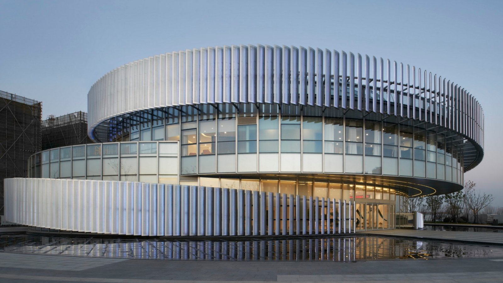 LINDELACR solid aluminum facade fins on a landmark circular building at dusk