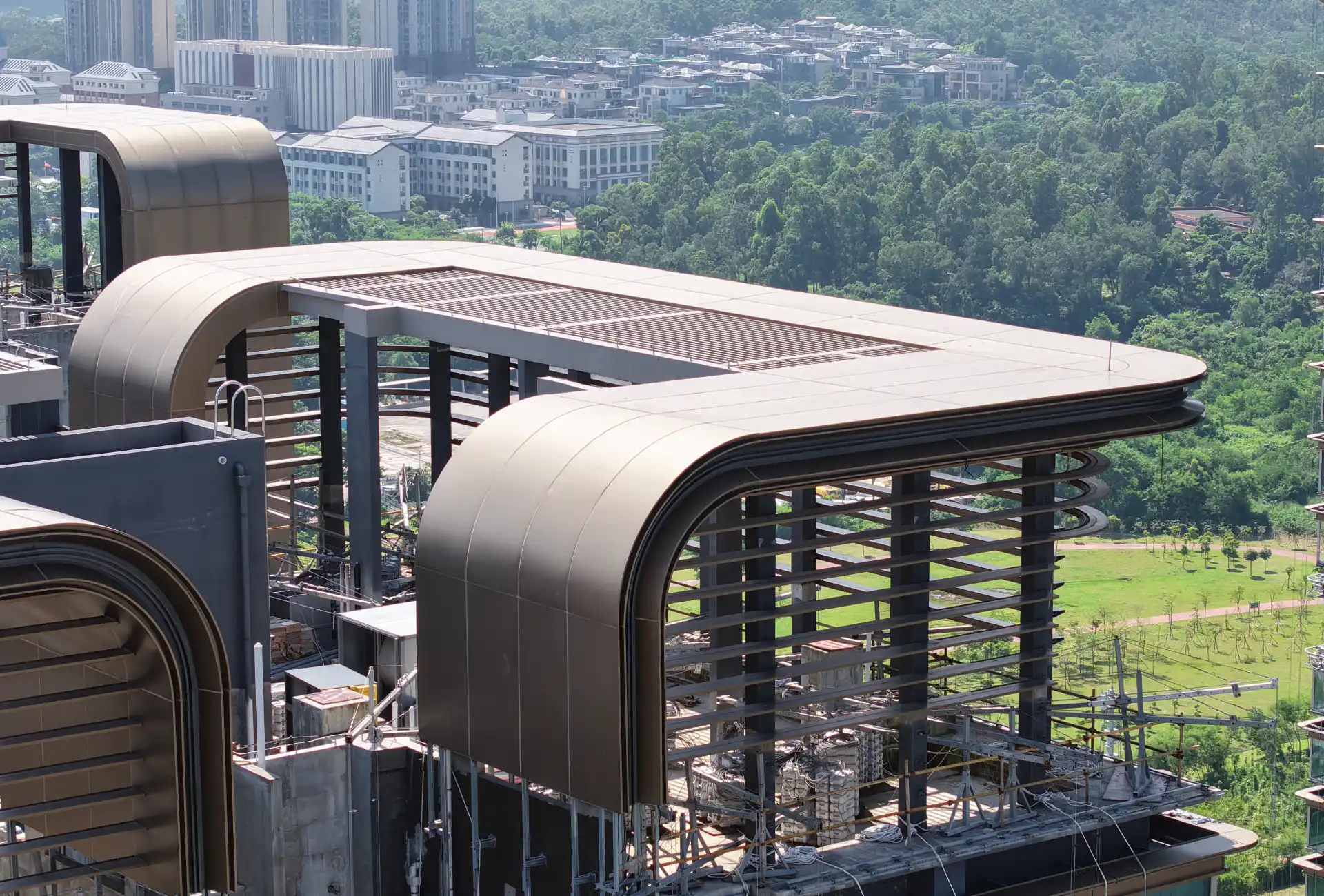 Curved bronze aluminum crown and louvered canopy on a tower, each radius a separate panel