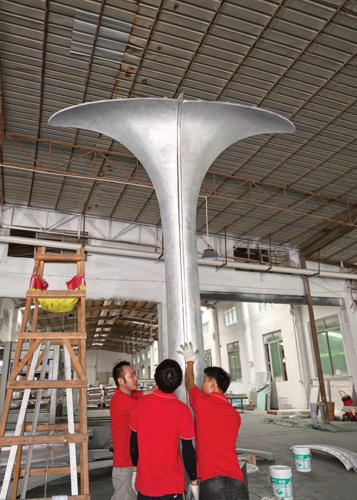 LINDELACR workers trial-assemble a silver flared aluminum column cover in the Foshan plant