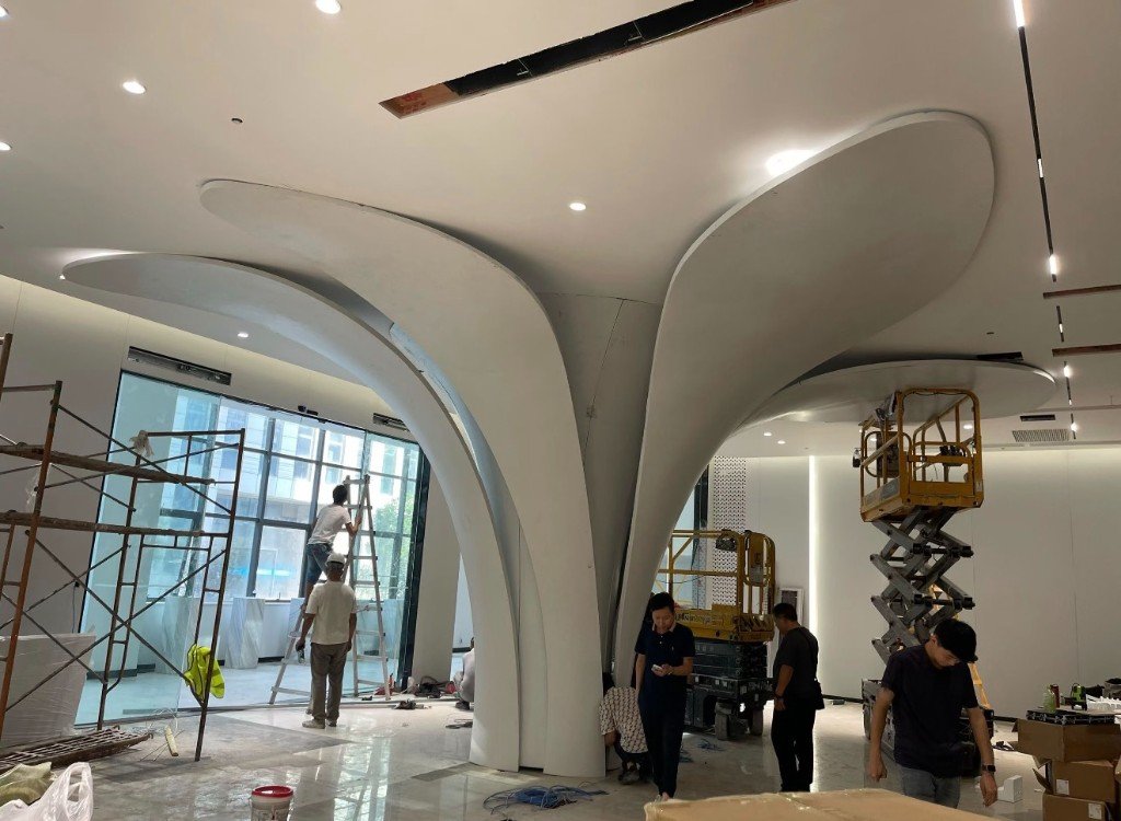 LINDELACR compound aluminum column and soffit petals being installed in a lobby, scissor lifts still on the floor