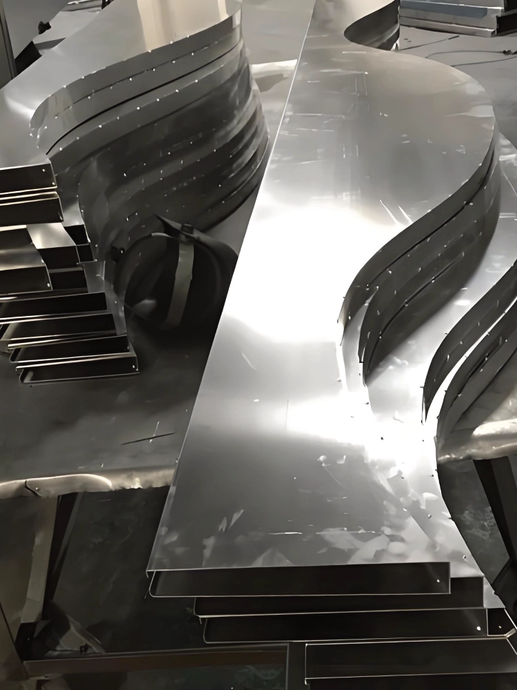 LINDELACR mill-finish curved aluminum baffles stacked in the Foshan shop before coating or wood-grain transfer