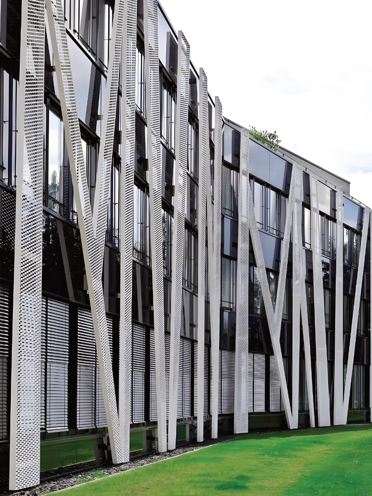 Custom white perforated aluminum fins on a commercial glass facade, CNC hole field reading as a sun screen