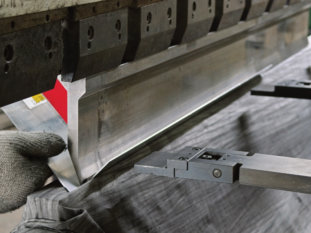 LINDELACR press brake folding an aluminum ceiling return: gloved hand holds the sheet against the die