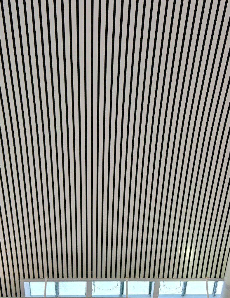 Black and white linear baffle ceiling seen from below, not a lay-in tile grid