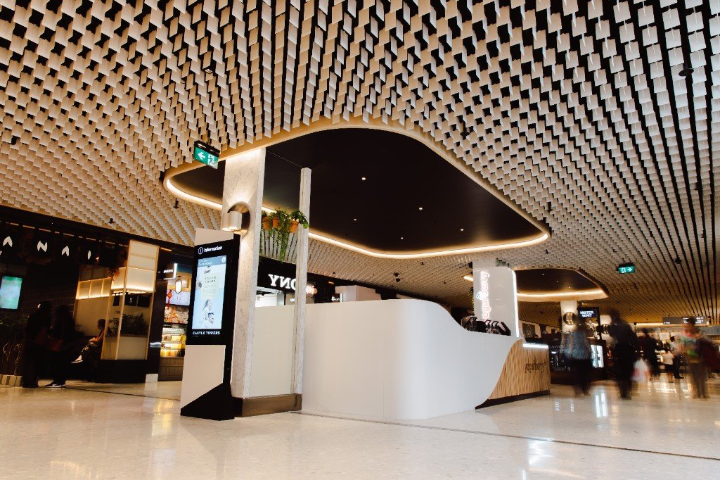 A curved black soffit cut through a radial field of aluminum blades in a mall concourse