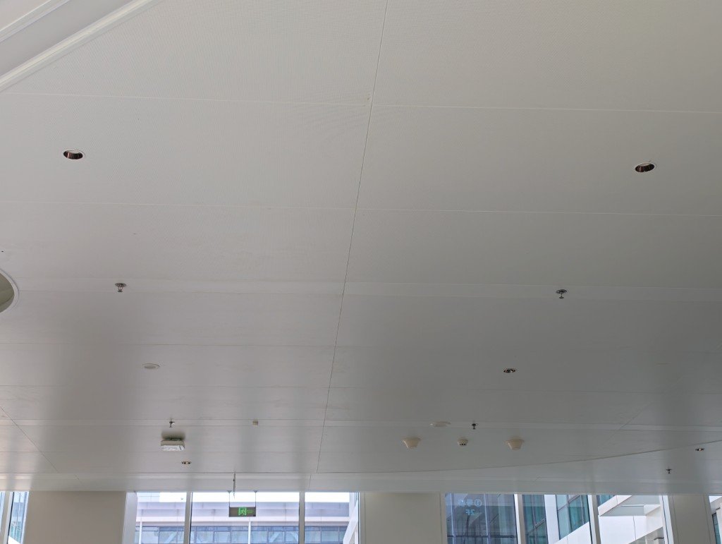 White modular aluminum ceiling with downlights, sprinklers, and detectors in an interior
